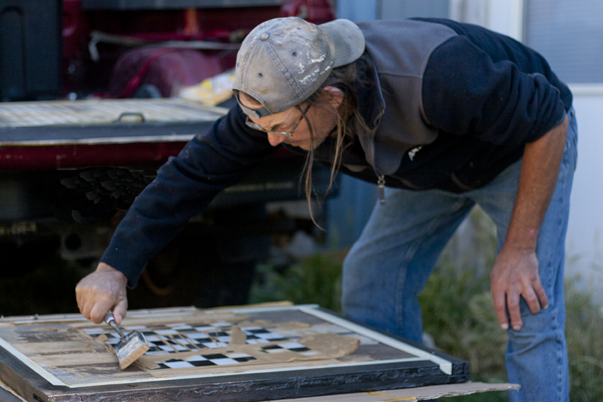 Mark Funk adds grout to the tile checker board table he has designed. Design by Mark Funk. Photo by Mary Anne Funk