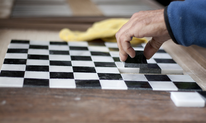 After cutting every square down to size and laying out the table, Mark lifted each piece to add thin set to every square before placing it back down.