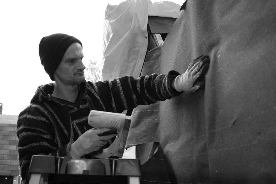 Joel adds tar paper to the outside of his shelter for weather proofing. Photo © 2016 Mary Anne Funk