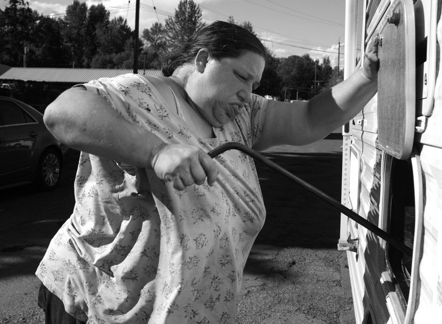 Katie digs deep as she manualy closes the side panel on their RV. A lack of electricity made it impossible for Katie to close the side panel on their RV prior to it being towed to their new location. When I commented to Katie that she was amazing, she replied, "We don't have much, but we have grit". Photo ©Mary Anne Funk Finding Home http://www.maryannefunk.com/photo-essays/finding-home-longaneckers/